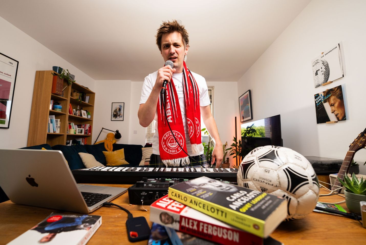 Man wearing an aberdeen FC scarf standing in a living room